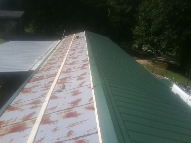 Old rusted panels beside newly installed green metal roofing — Wind Damage Roof Repair by Roofing Brothers in Leechburg