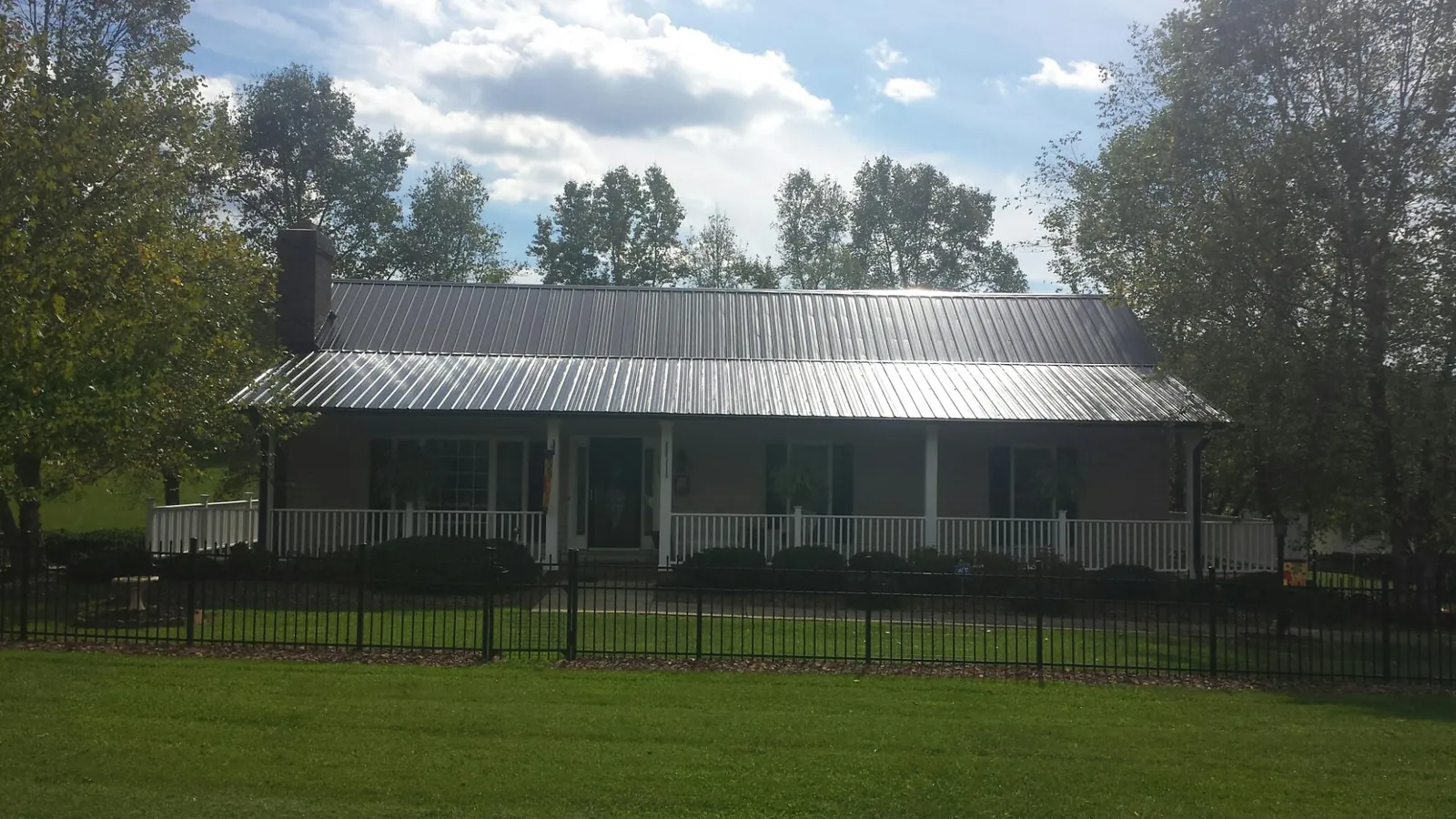 Gray metal roof on a brick ranch with a full width front porch — Gutter Guard Installation work by our crew in Leechburg