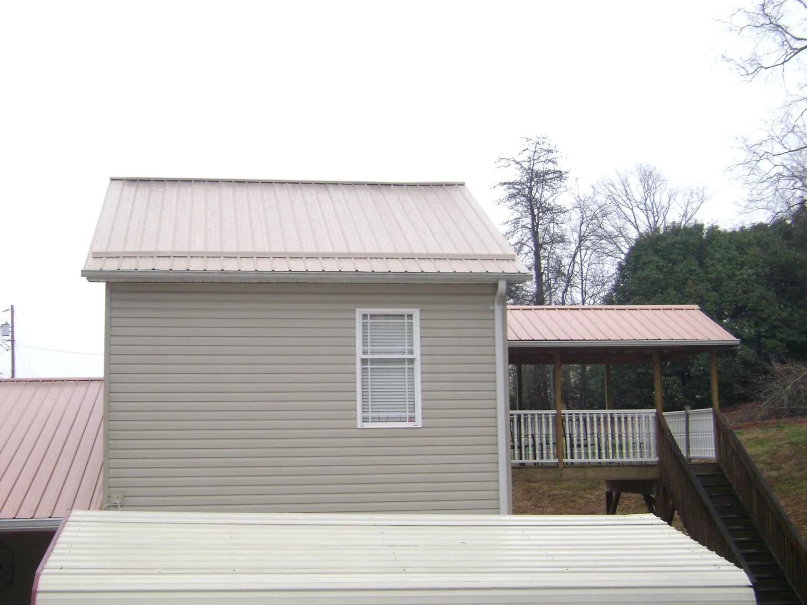Tan metal roofs on a two story addition and attached porch, from a Roof Replacement job in Leechburg