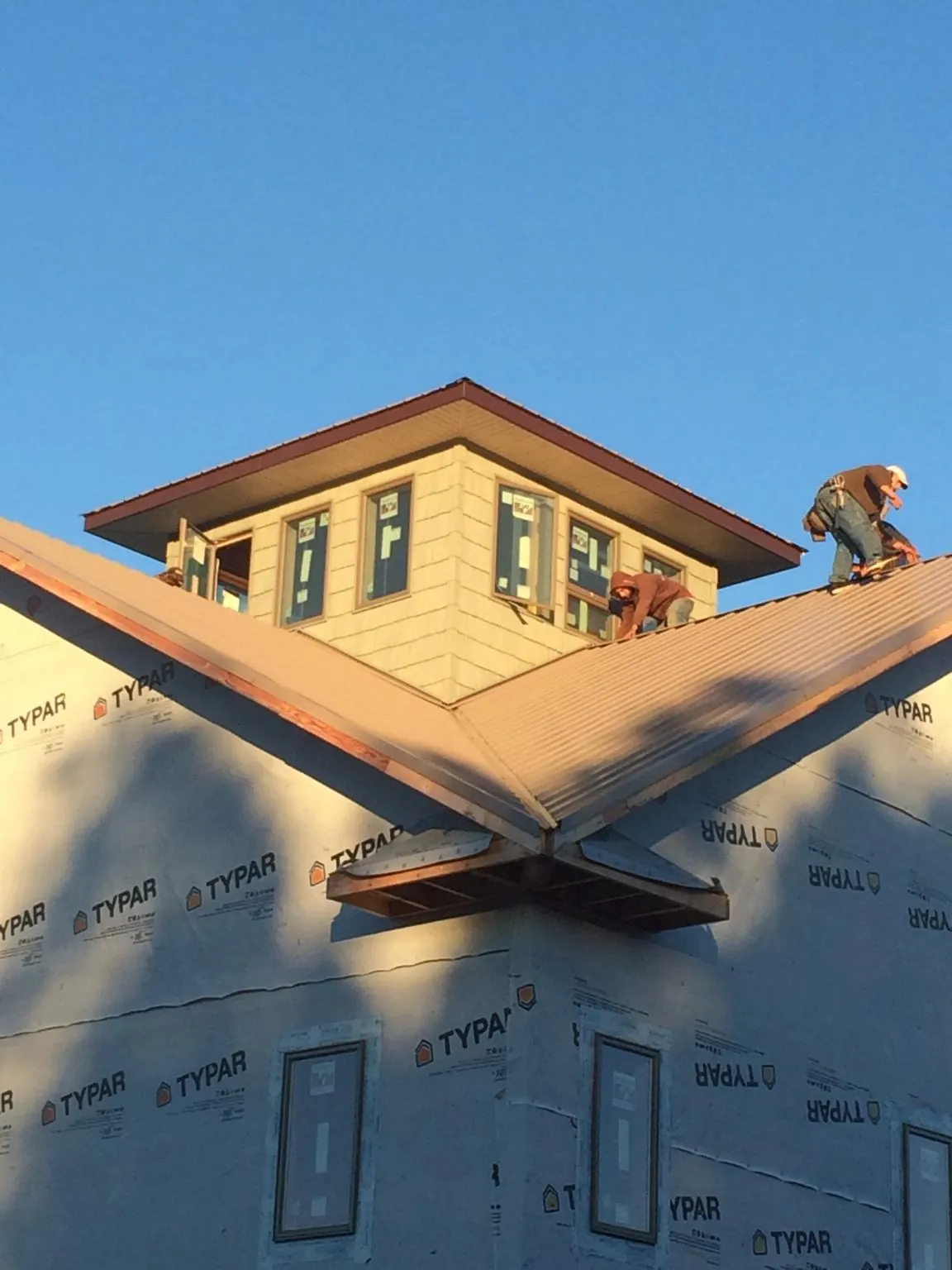 Roofers working around a rooftop cupola on a new metal roof at sunset — Roof Waterproofing in Leechburg by Roofing Brothers
